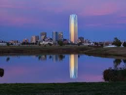 City skyline reflected in calm water during sunset.