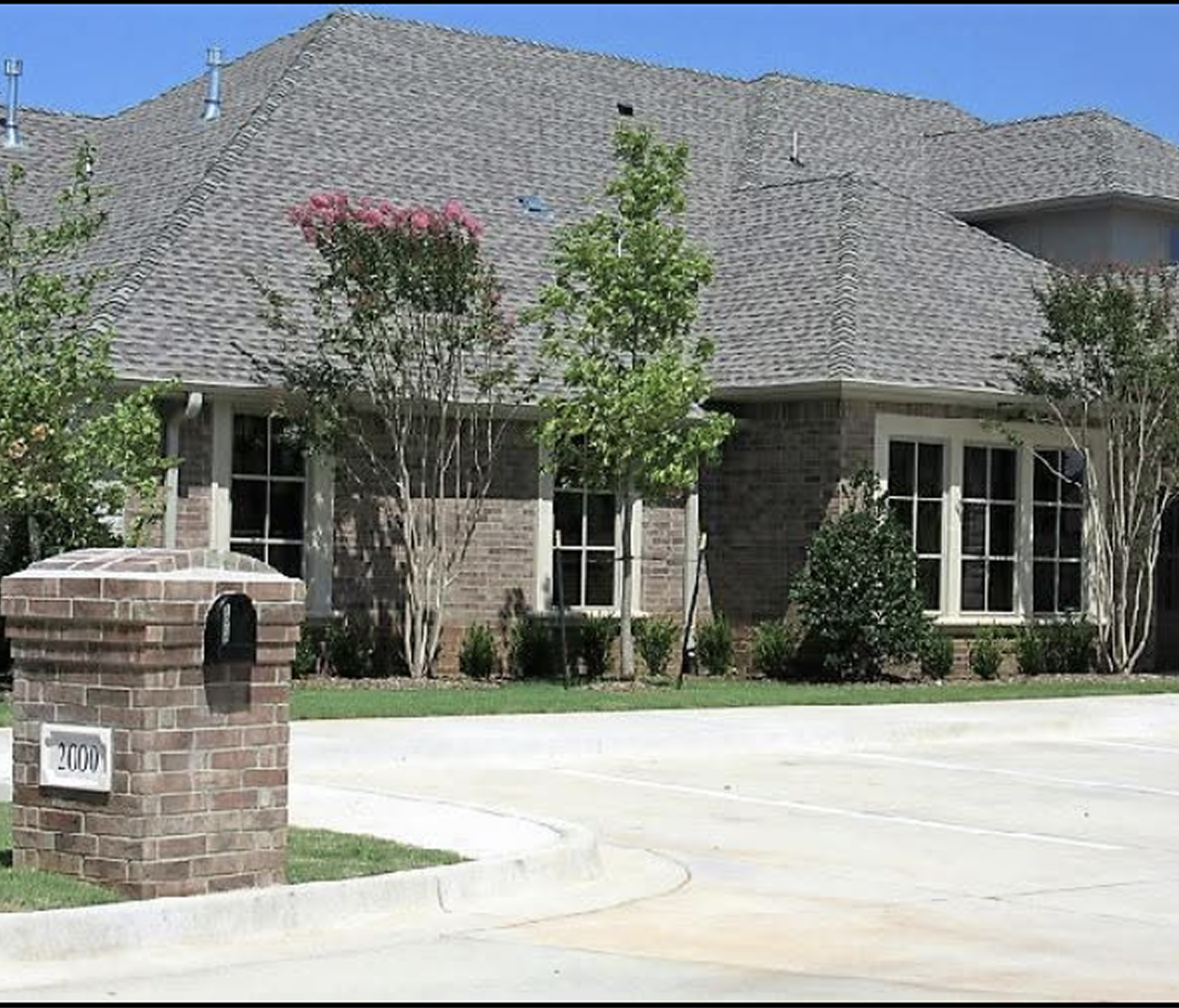 Modern suburban house with brick accents and a well-maintained lawn.